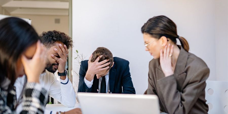 Equipo de trabajo con signos de estrés y agotamiento en una oficina