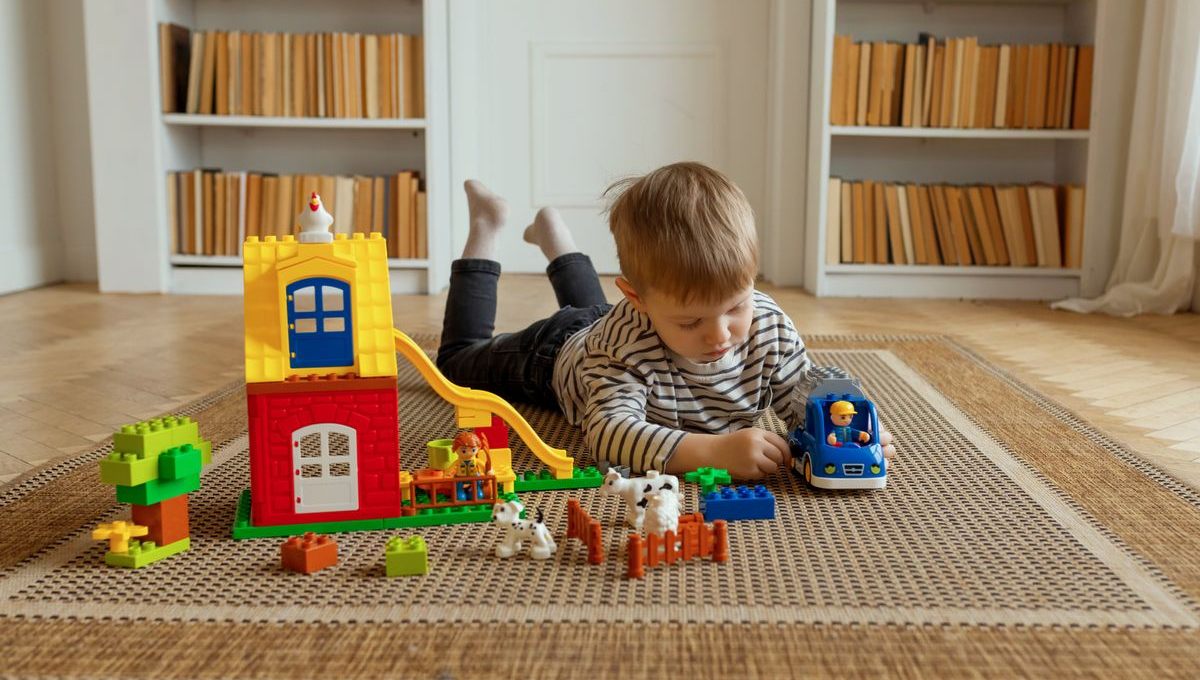 Niño jugando concentrado en el piso con bloques de construcción